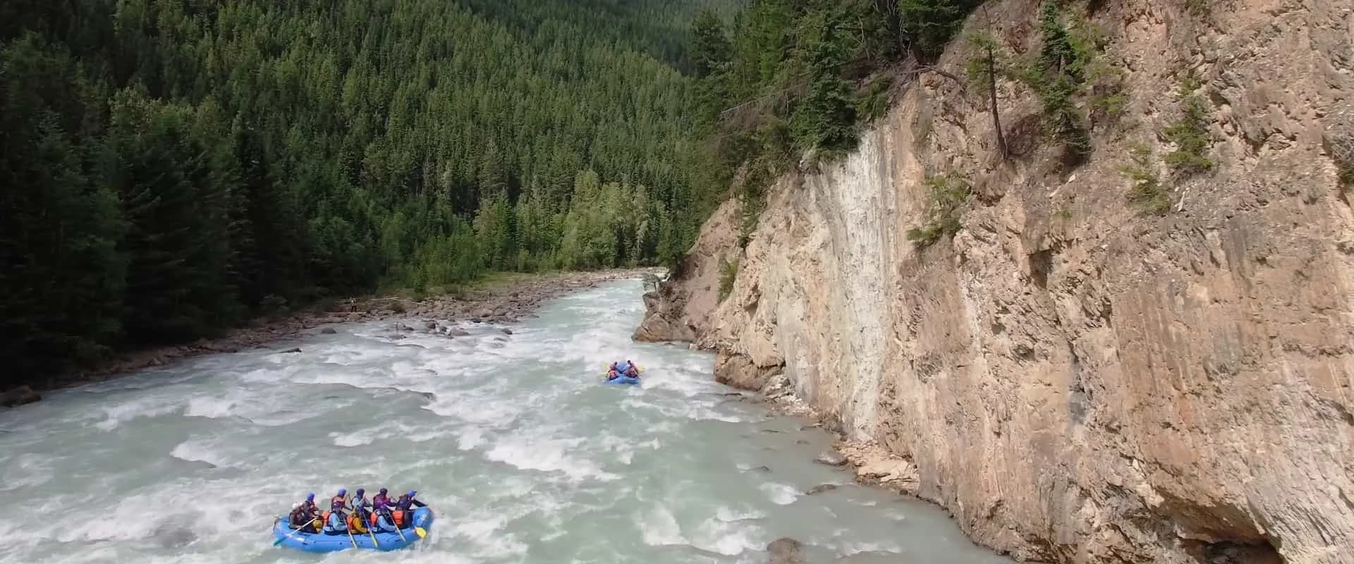 A raft running whitewater beneath tall canyon walls on the Kicking Horse River